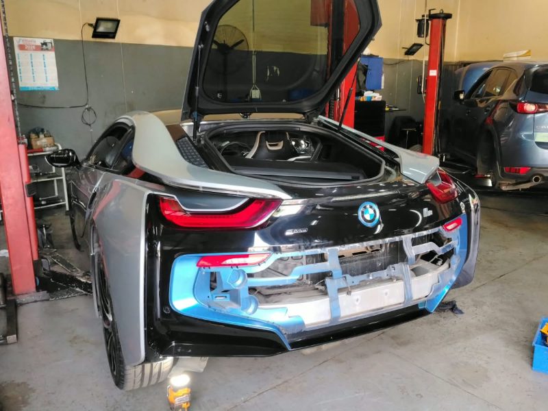 A BMW i8 with its rear bumper off in the Q&A Auto Repairs workshop